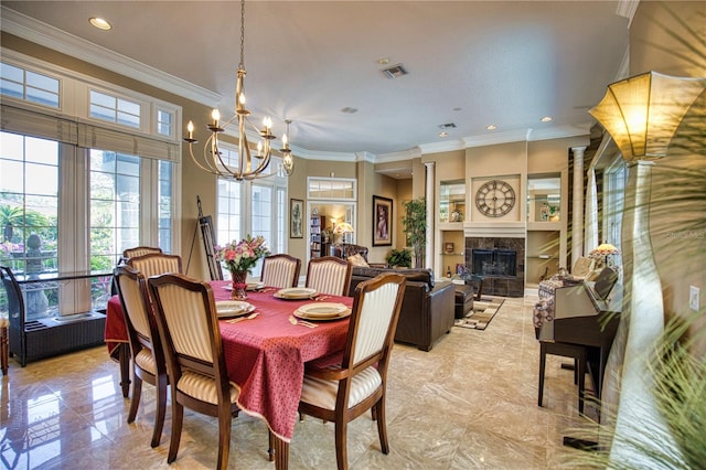 dining room with a notable chandelier, ornamental molding, and a tiled fireplace