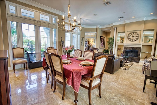 dining room with a tiled fireplace, a chandelier, and ornamental molding