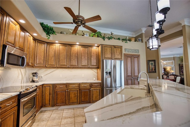 kitchen featuring pendant lighting, sink, ornamental molding, light stone counters, and stainless steel appliances