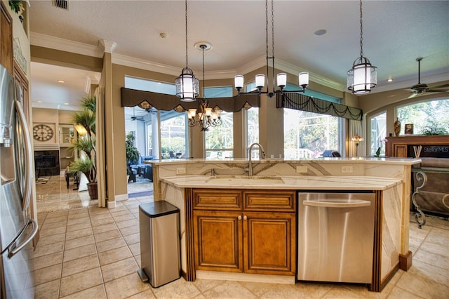 kitchen with a kitchen island with sink, sink, a healthy amount of sunlight, and decorative light fixtures