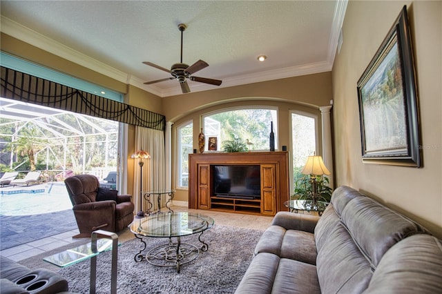 living room with ceiling fan, tile patterned flooring, a textured ceiling, and ornamental molding