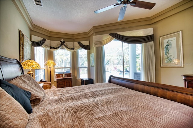 bedroom featuring ceiling fan, crown molding, and a textured ceiling