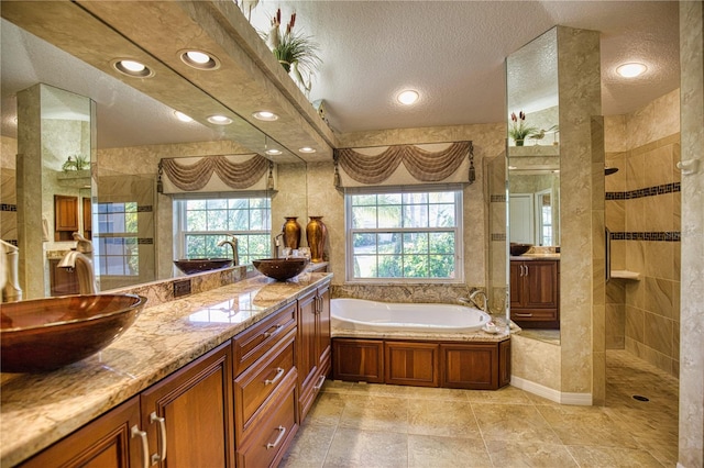 bathroom featuring plus walk in shower, vanity, and a textured ceiling