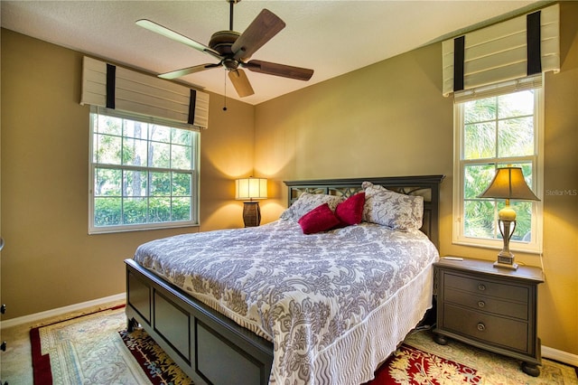 carpeted bedroom with ceiling fan and multiple windows