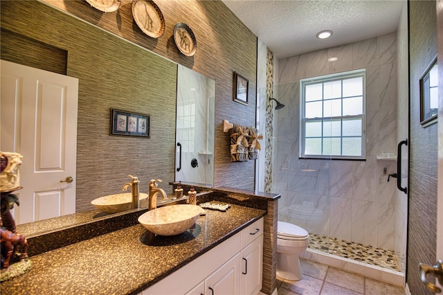 bathroom featuring vanity, toilet, tile walls, a textured ceiling, and walk in shower