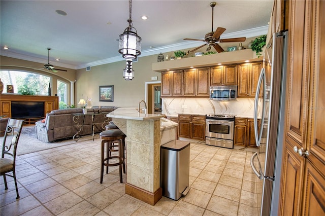 kitchen featuring a breakfast bar, crown molding, stainless steel appliances, and a kitchen island with sink