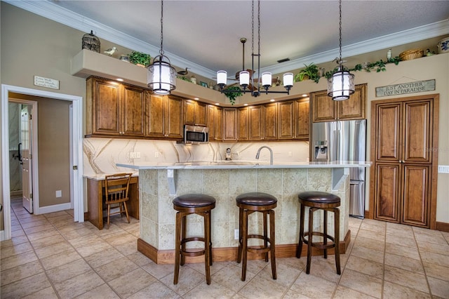 kitchen with a breakfast bar, stainless steel appliances, a kitchen island with sink, crown molding, and sink