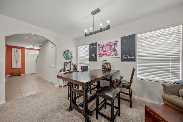 dining space featuring light carpet, a textured ceiling, and a notable chandelier