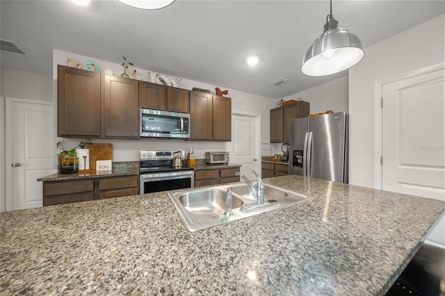 kitchen with dark brown cabinetry, sink, hanging light fixtures, and appliances with stainless steel finishes