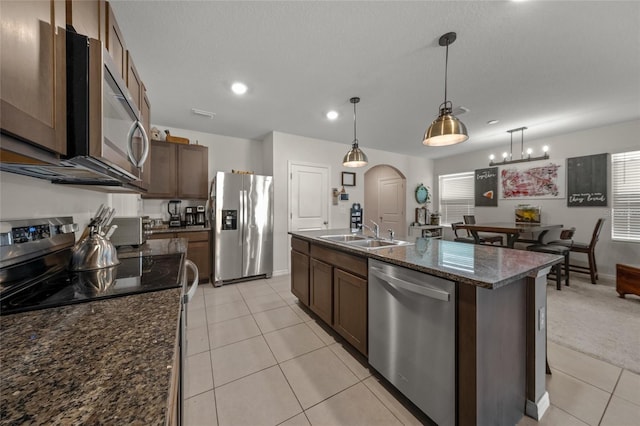 kitchen featuring pendant lighting, sink, dark stone countertops, an island with sink, and stainless steel appliances