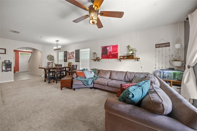 living room featuring ceiling fan with notable chandelier, light colored carpet, and a textured ceiling