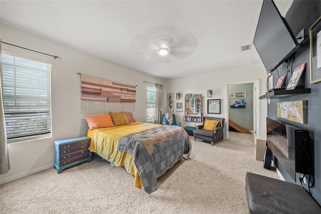 bedroom with multiple windows, ceiling fan, carpet floors, and a textured ceiling