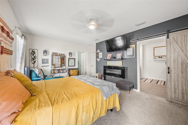 bedroom with a barn door, ceiling fan, and carpet