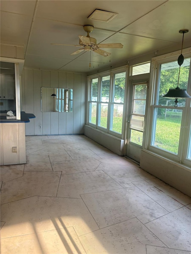 unfurnished sunroom featuring ceiling fan and a healthy amount of sunlight