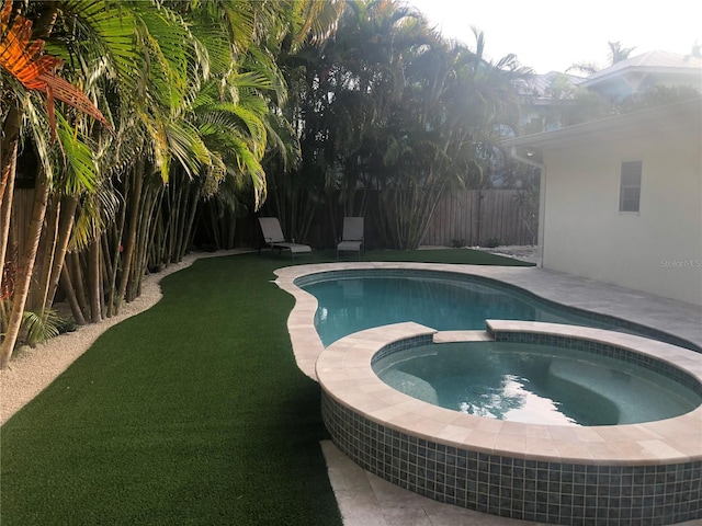 view of swimming pool featuring a lawn and an in ground hot tub