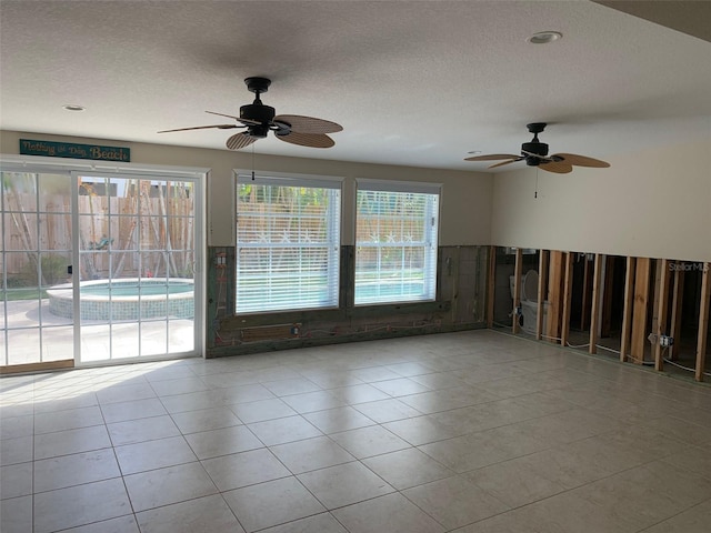 tiled empty room featuring ceiling fan and a textured ceiling