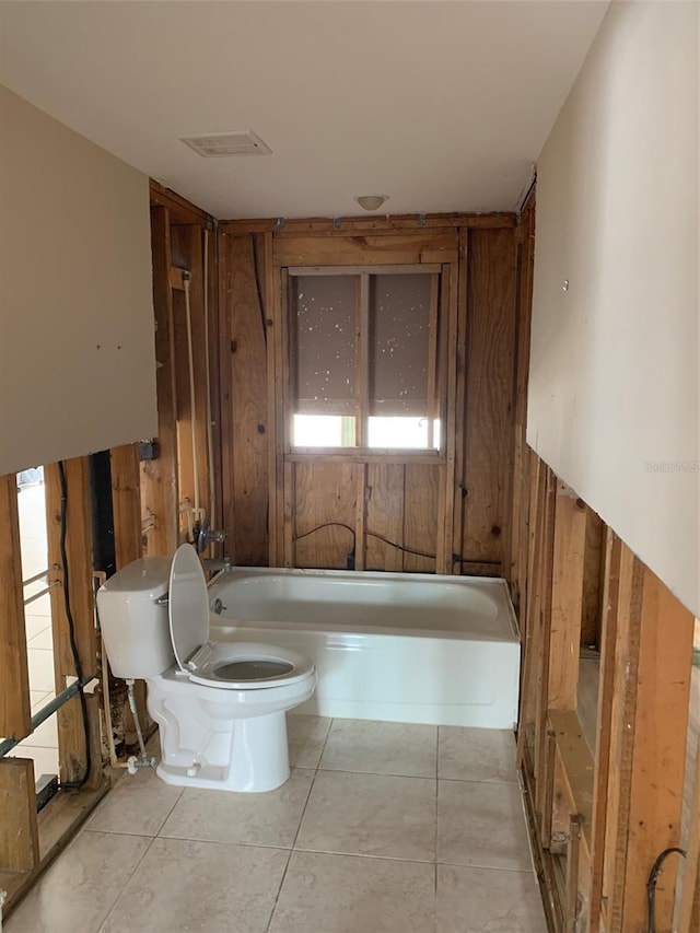 bathroom with tile patterned flooring, wood walls, toilet, and a tub to relax in