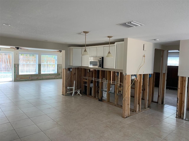 kitchen featuring white cabinetry, pendant lighting, ceiling fan, and a healthy amount of sunlight