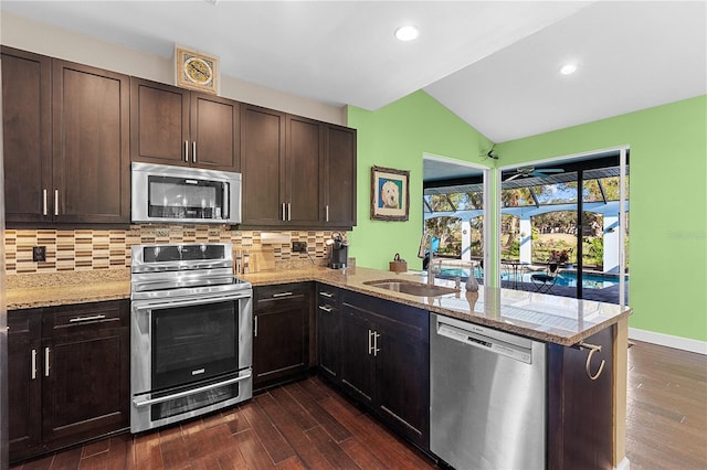 kitchen with kitchen peninsula, decorative backsplash, stainless steel appliances, and light stone countertops