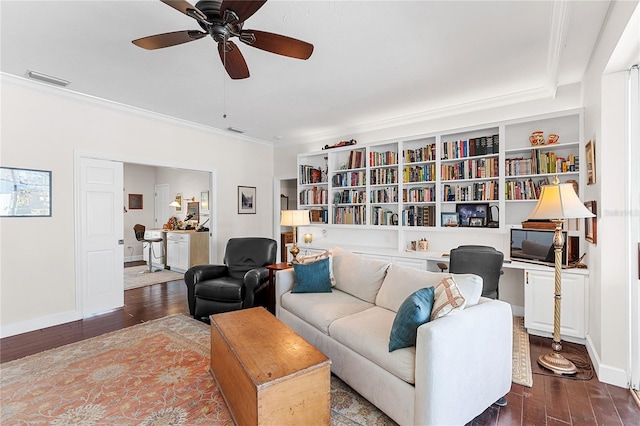 living room featuring built in shelves, dark hardwood / wood-style floors, ceiling fan, and crown molding