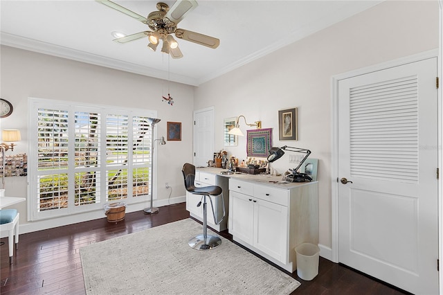 office area with ceiling fan, built in desk, ornamental molding, and dark wood-type flooring