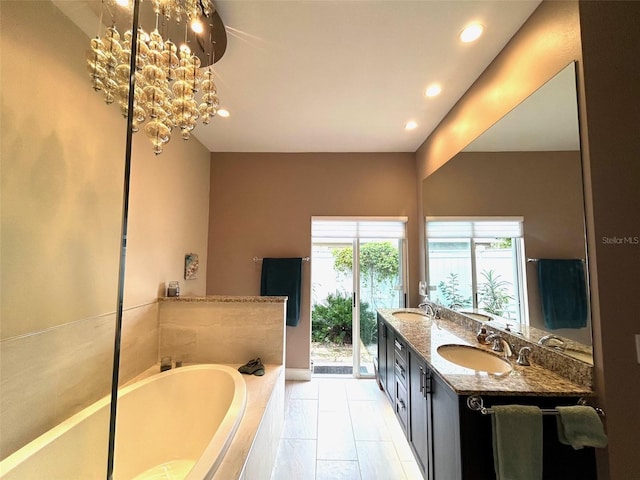 bathroom featuring vanity, a relaxing tiled tub, and an inviting chandelier