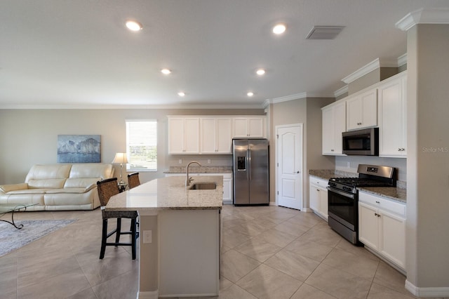 kitchen featuring an island with sink, sink, white cabinets, stainless steel appliances, and light stone countertops