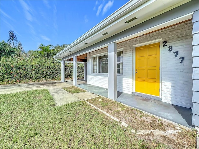 doorway to property featuring a porch and a lawn