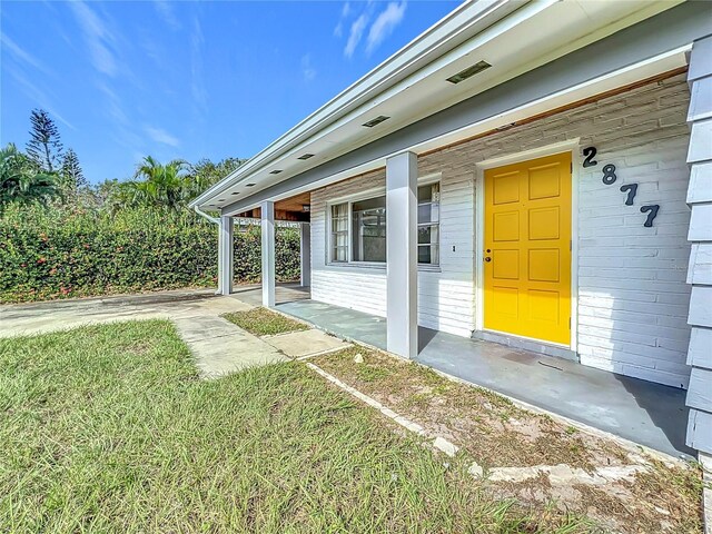 2877 Michigan St, Sarasota, FL 34237 - view of exterior entry featuring a yard and a porch
