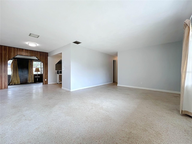 unfurnished living room featuring wood walls