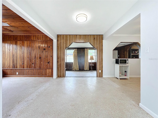 unfurnished living room with beamed ceiling and wooden walls