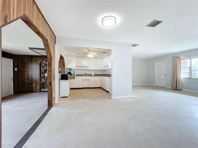 unfurnished living room with ceiling fan, sink, and wooden walls