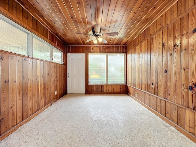 unfurnished room with light colored carpet, wood ceiling, ceiling fan, and wood walls