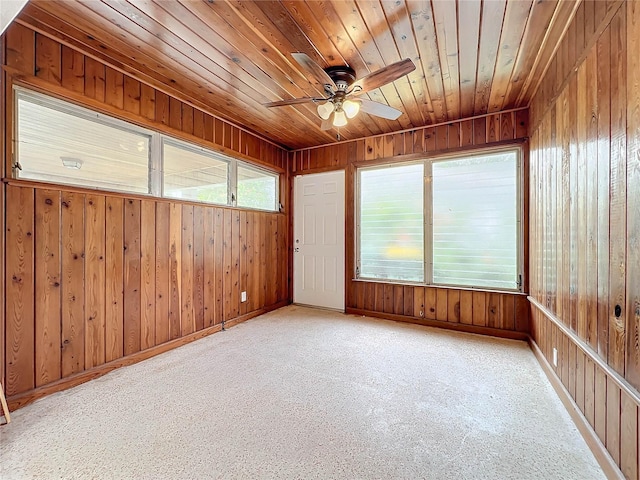 carpeted spare room with wooden ceiling and wood walls