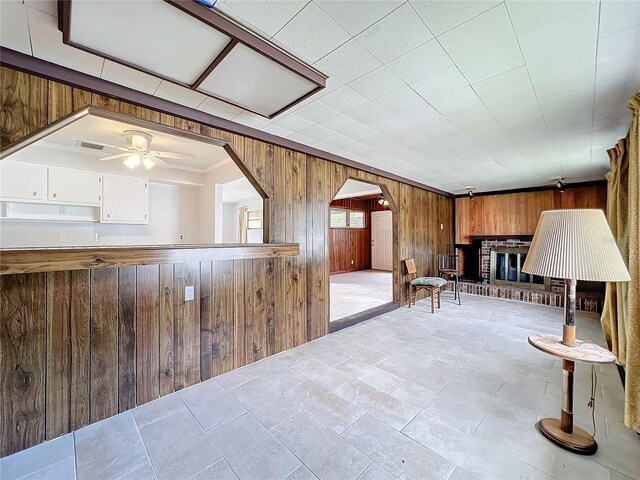 2877 Michigan St, Sarasota, FL 34237 - sitting room featuring wood walls, a ceiling fan, a brick fireplace, ornamental molding, and arched walkways