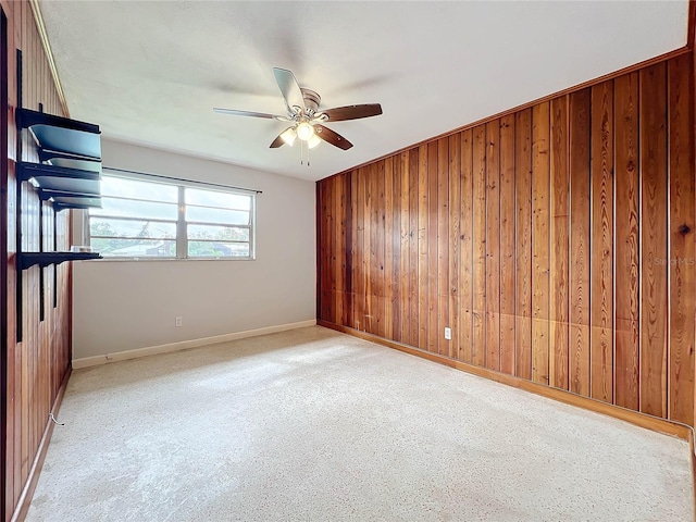 carpeted empty room with ceiling fan and wood walls