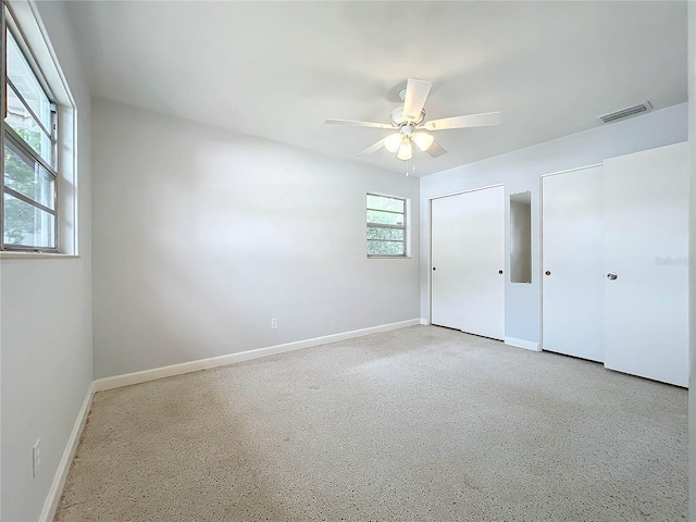 unfurnished bedroom featuring ceiling fan and two closets