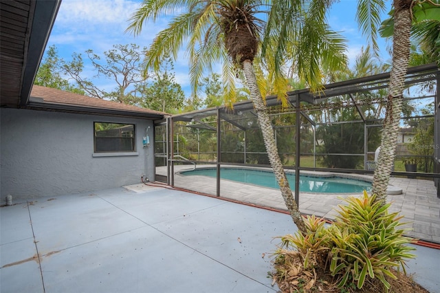 view of swimming pool featuring glass enclosure and a patio area