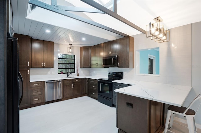 kitchen with pendant lighting, sink, dark brown cabinets, black appliances, and kitchen peninsula