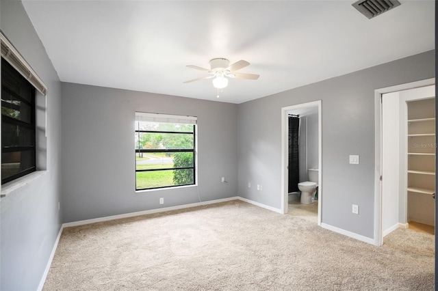 unfurnished bedroom with ceiling fan, connected bathroom, and light carpet