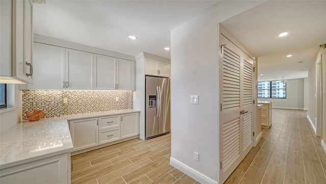 kitchen featuring decorative backsplash, light hardwood / wood-style floors, white cabinetry, and stainless steel refrigerator with ice dispenser