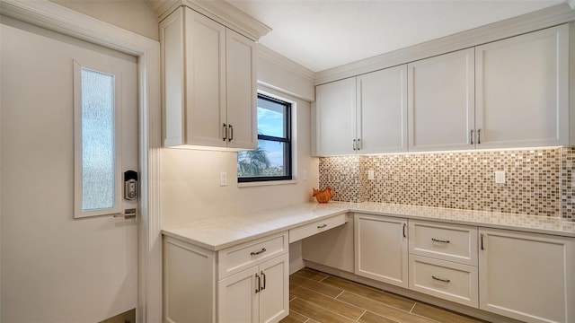 5760 Midnight Pass Rd Unit 307D, Sarasota, FL 34242 - kitchen featuring decorative backsplash, light wood finished floors, white cabinets, light stone countertops, and crown molding