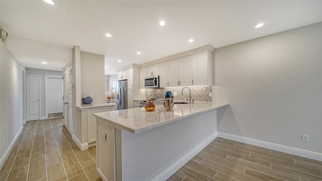 5760 Midnight Pass Rd Unit 307D, Sarasota, FL 34242 - kitchen featuring stainless steel appliances, light wood-style flooring, a peninsula, backsplash, and recessed lighting