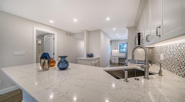 kitchen featuring light stone countertops, sink, dark wood-type flooring, decorative backsplash, and white cabinets