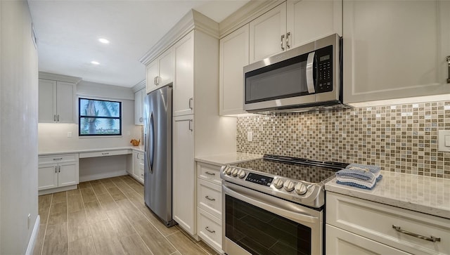 kitchen with light wood-type flooring, backsplash, light stone counters, stainless steel appliances, and white cabinets