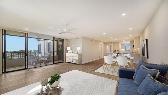 living room with floor to ceiling windows, hardwood / wood-style floors, and ceiling fan