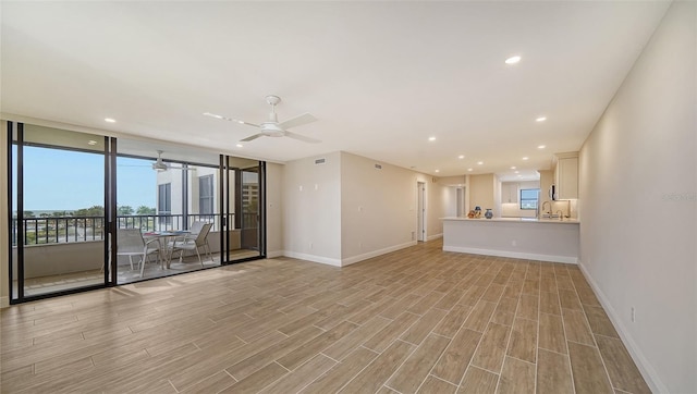 unfurnished living room with light hardwood / wood-style flooring, ceiling fan, and sink