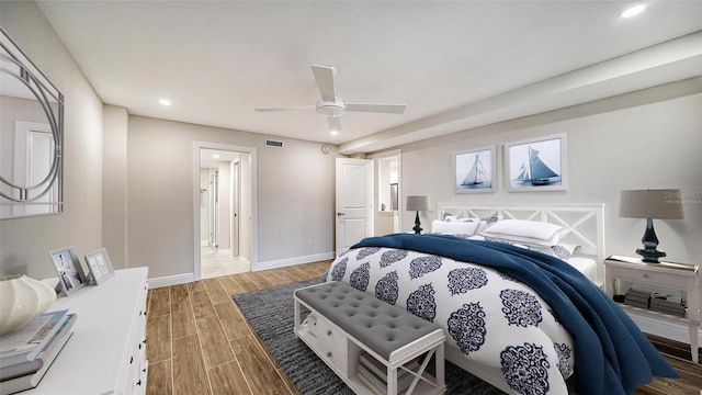 bedroom with hardwood / wood-style floors, ceiling fan, and connected bathroom