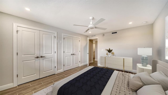 bedroom featuring multiple closets, ceiling fan, and hardwood / wood-style flooring