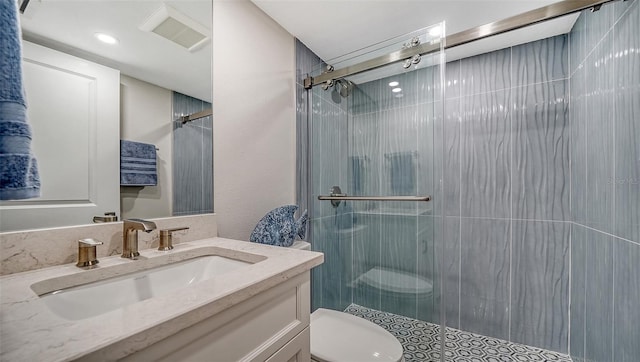 bathroom with a shower with door, vanity, and toilet